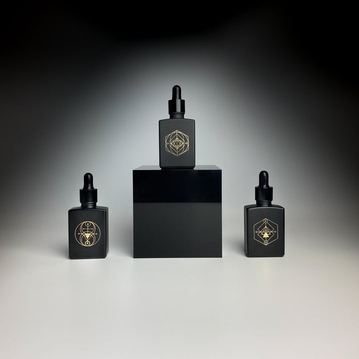 three black glass perfume bottles, Gold Shemana coding, Gold logo, Elixir, 