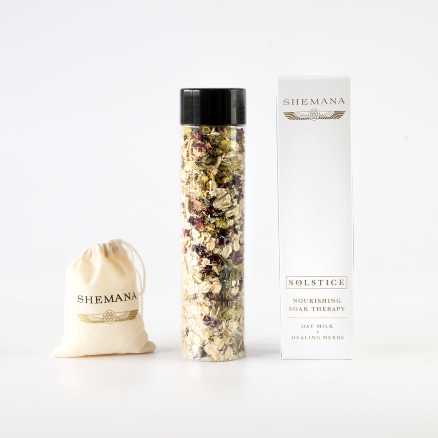 tall white box, gold Shemana logo, Solstice, tall plastic bottle filled with herbs and flowers and oaks, small cotton bag with Shemana logo