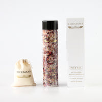 white box, shemana logo, tall plastic bottle filled with pink bath salts and wildflowers, black  lid, shemana cotton small bag